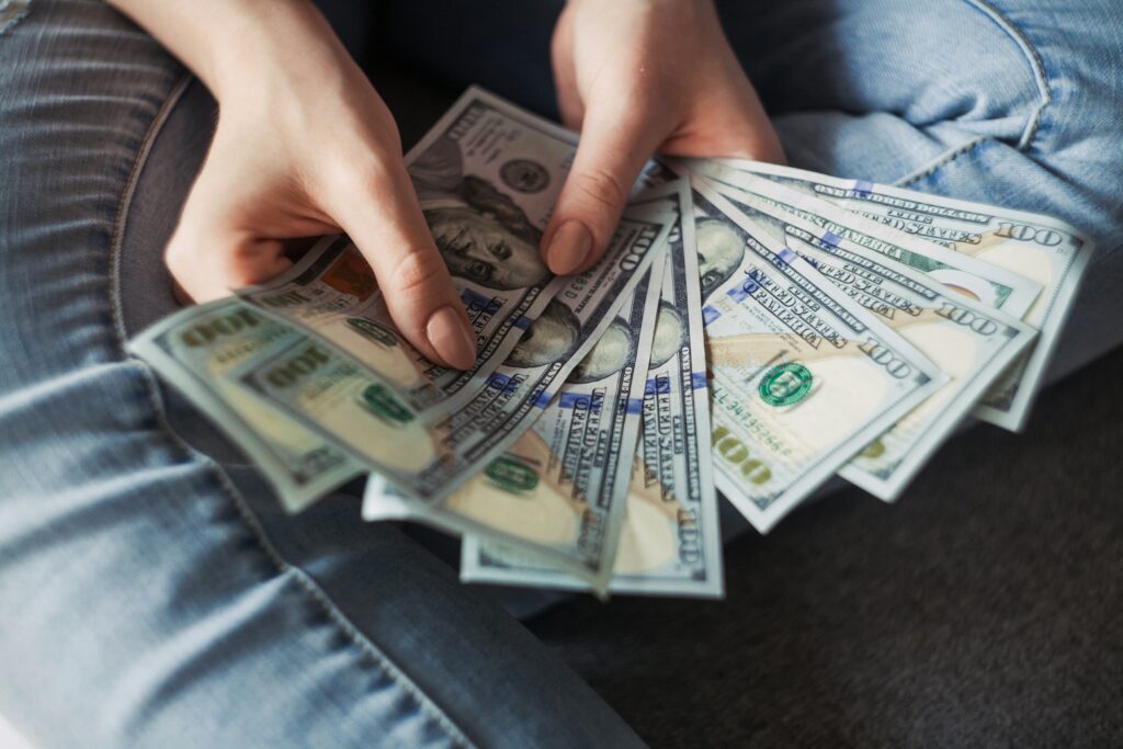 a person holding a handful of $100 dollar bills